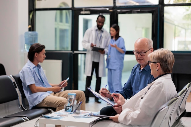 Premium Photo | Senior specialist sitting on chair in hospital lobby ...