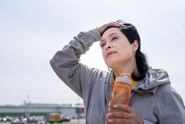 Senior sport actieve senioren senior vrouw vegen zweet uit na een zware workout buiten in het park