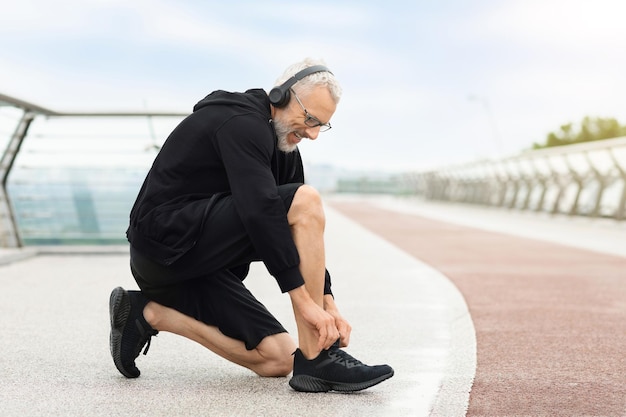 Senior sportman buig knie fix schoenveters nieuwe kwaliteit sneakers