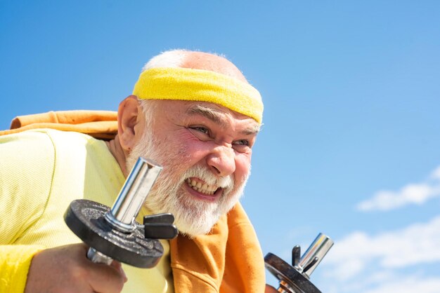 Senior sportman lifting dumbbells close up portrait Elderly man workout