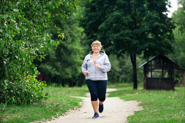 写真 トラック上の公園で走っているシニアスポーツ女性