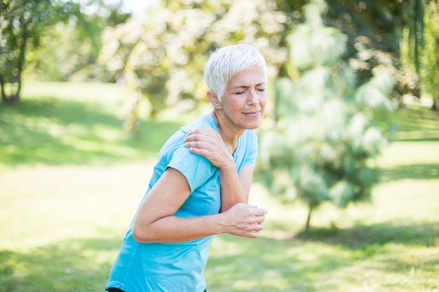 Senior sporty woman having shoulder pain