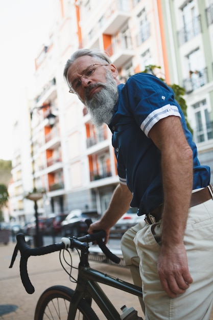 Foto senior stijlvolle bebaarde man fietsen op straten van de stad