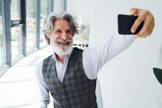 Senior stijlvolle moderne man met grijs haar en baard binnenshuis