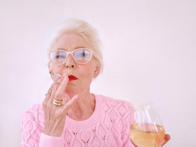 Senior stijlvolle vrouw roken sigaret met glas witte wijn