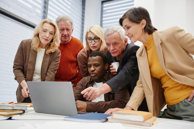 Senior studenten leren nieuw computerprogramma op laptop