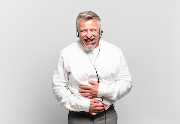 Senior telemarketer laughing out loud at some hilarious joke, feeling happy and cheerful, having fun