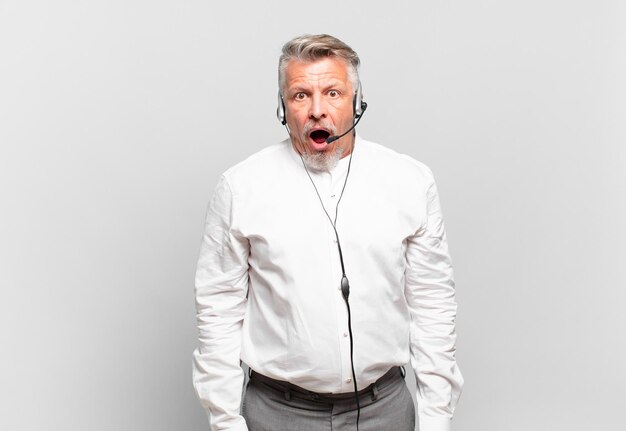 Senior telemarketer looking very shocked or surprised, staring with open mouth saying wow