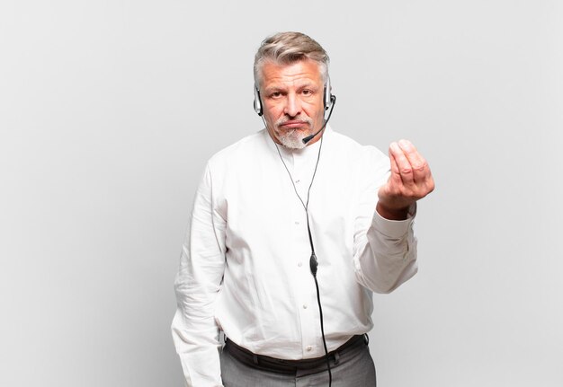 Senior telemarketer making capice or money gesture, telling you to pay your debts!