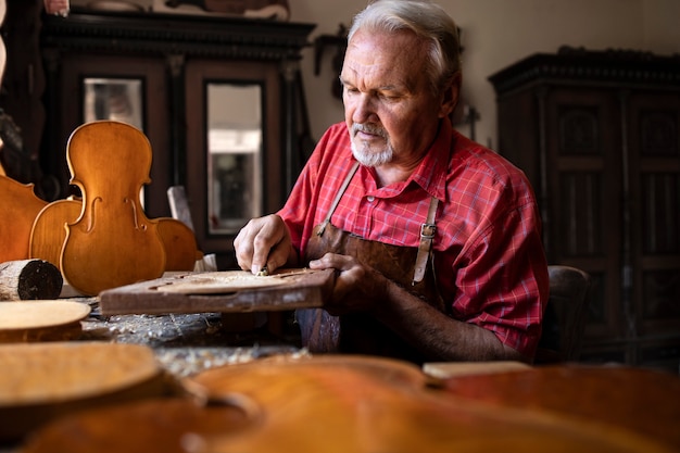 Senior timmerman ambachtsman zorgvuldig hout snijden en vormgeven in zijn houtbewerkingsatelier.