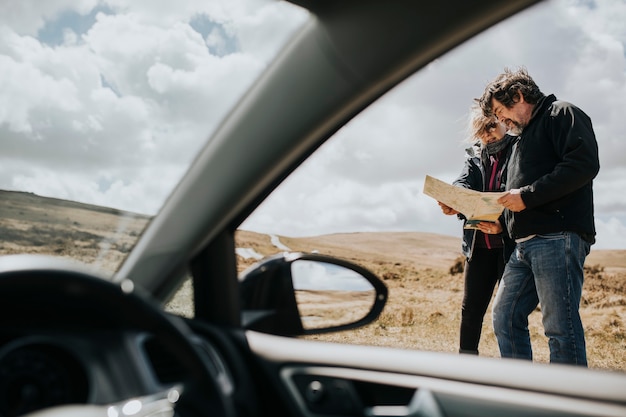 Senior tourist couple looking at the map while being lost in Wales, UK