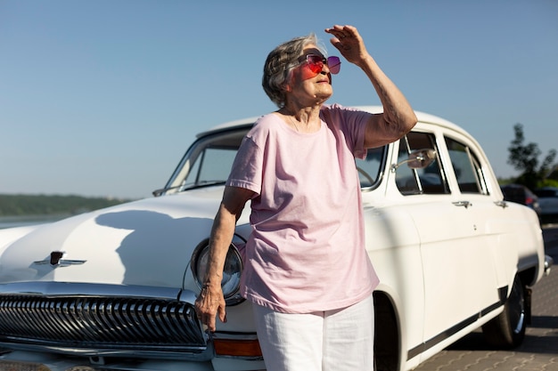 Photo senior traveler standing nest to her car