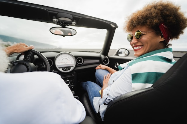 休日の時間にコンバーチブル車の中でシニアトレンディなカップル-女性の顔に焦点を当てる