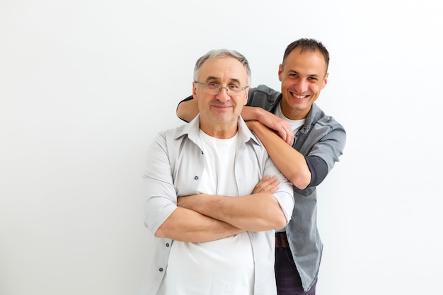 Senior vader met volwassen zoon op een witte muur