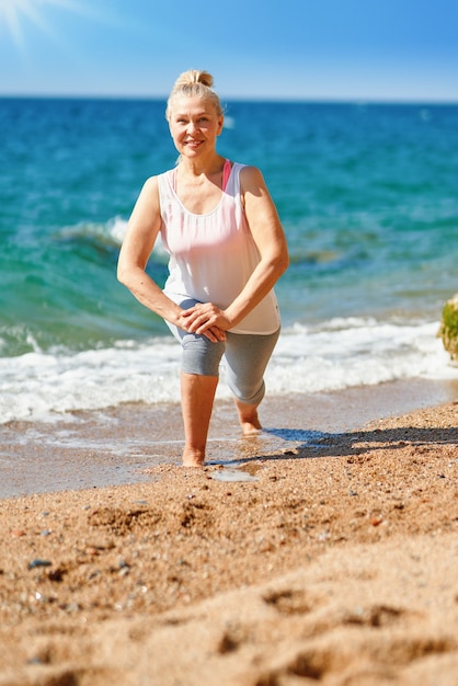 Senior volwassen aantrekkelijke vrouw tijdens sporten aan zee