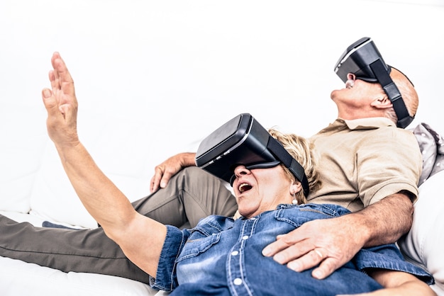 Senior volwassen paar plezier samen met virtual reality headset zittend op de bank