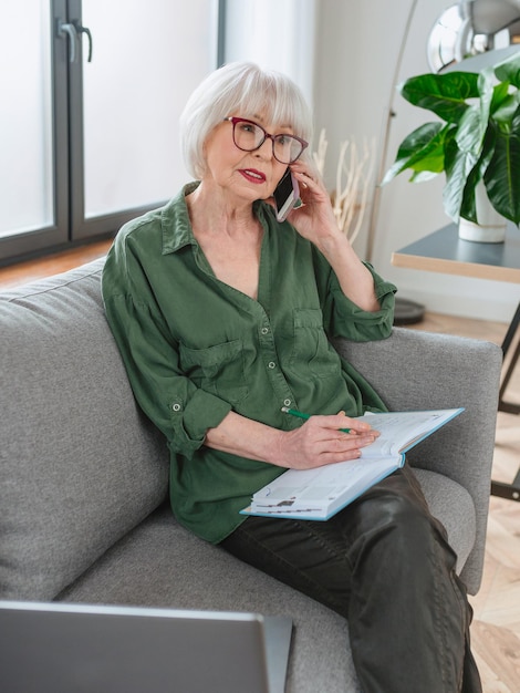 senior vriendelijke vrouw ondernemer werkt vanuit huis Praten aan de telefoon werken met laptop