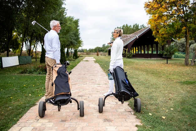 Senior vrienden met golfuitrusting lopen naar de baan om te gaan golfen.