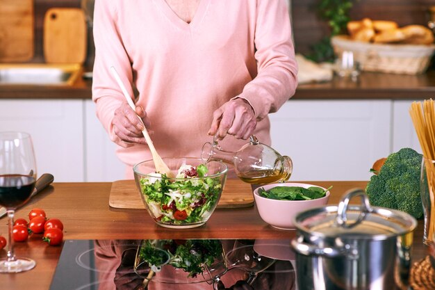 senior vrolijke vrouw kookt in de moderne keuken