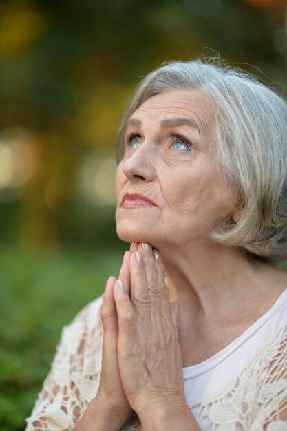 Senior vrouw bidden in park