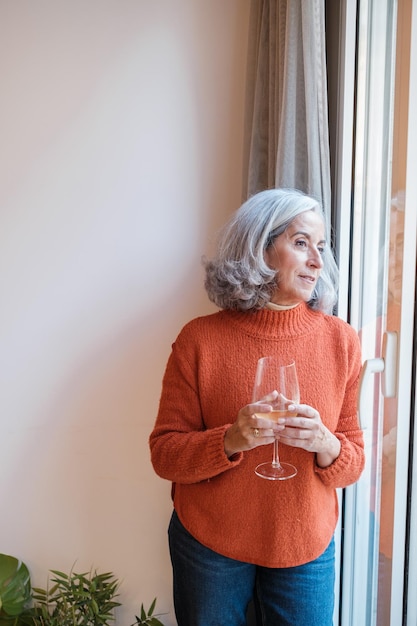 Senior vrouw die een pauze neemt, thuis een glas wijn drinkt en alleen ontspant Concept relax rest disconnection