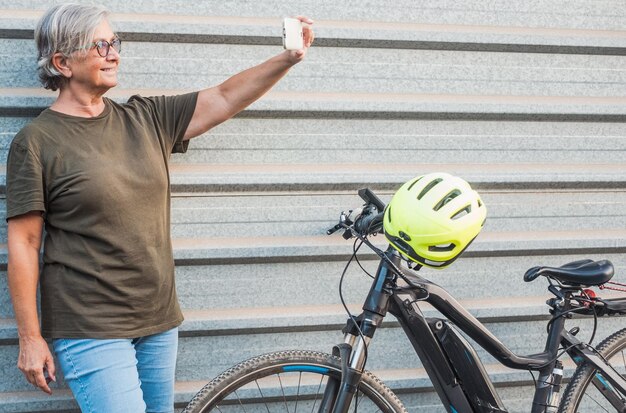 Foto senior vrouw die een selfie maakt terwijl ze tegen de muur staat