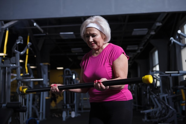 Senior vrouw die gefocust kijkt terwijl ze bicep-krullen doet