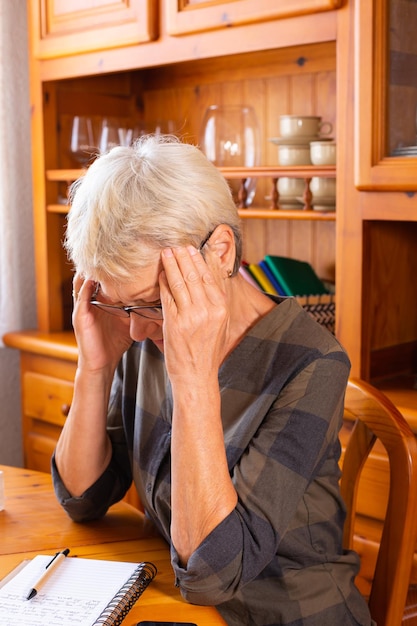 Senior vrouw die hoofdpijn heeft tijdens het maken van aantekeningen