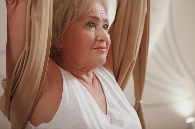 Senior vrouw die luchtyoga beoefent in sportstudio