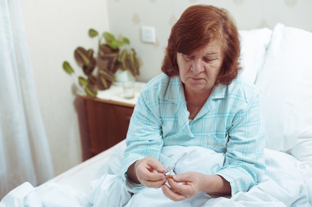 Senior vrouw die pil in bed neemt