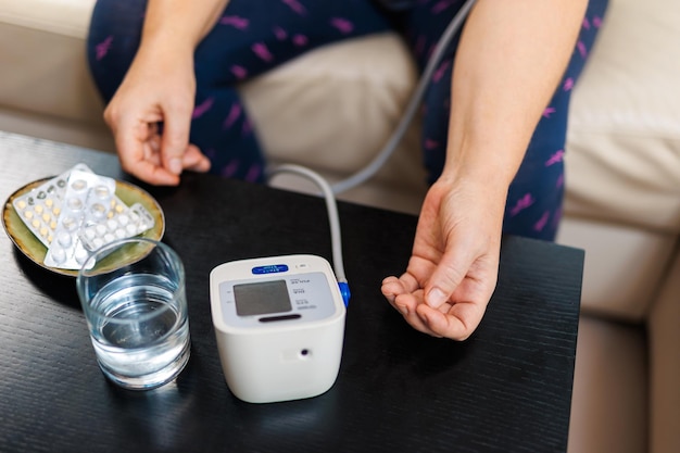 Senior vrouw die thuis de bloeddruk controleert oudere vrouw die lijdt aan hoge bloeddruk zittend op een bank en een pulsometer tonometer gebruikt