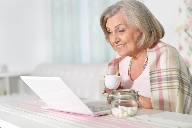 Senior vrouw die thuis met laptop werkt