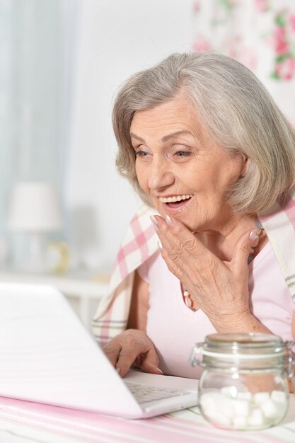 Senior vrouw die thuis met laptop werkt