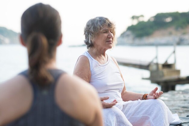 Senior vrouw doet een yoga-oefening aan de kust