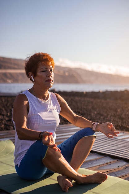 Senior vrouw doet meditatie aan zee