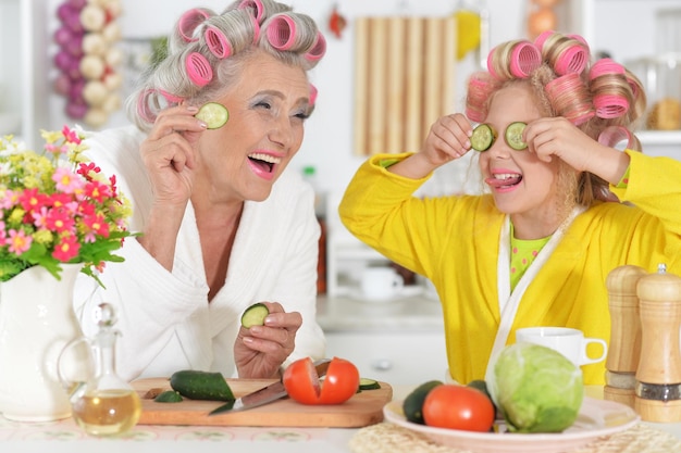 Senior vrouw en meisje met roze haarkrulspelden op het hoofd