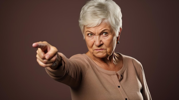 Senior vrouw, gekleed in vrijetijdskleding, wijzend met hand en vinger naar de zijkant, kijkend naar de camera