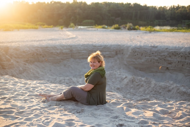 Senior vrouw gepensioneerde zitten in de natuur op zand