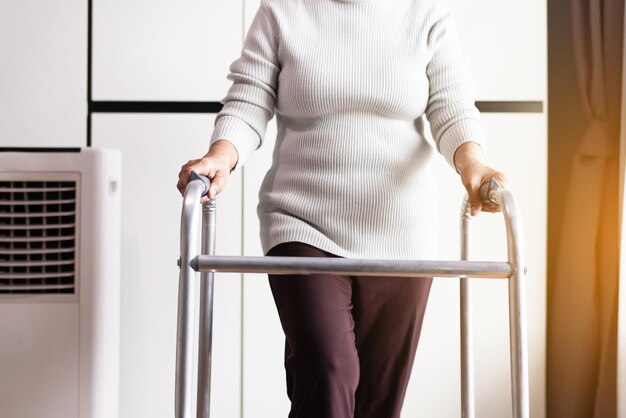 Senior vrouw handen met rollator die probeert thuis te lopen, concept voor fysiotherapie