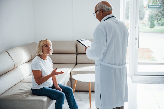 Senior vrouw heeft overleg in de kliniek door de mannelijke arts.