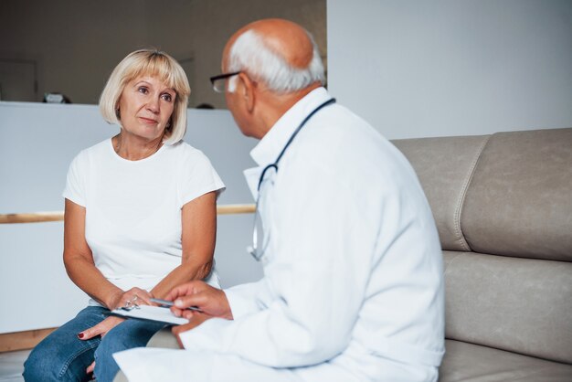 Senior vrouw heeft overleg in de kliniek door de mannelijke arts.