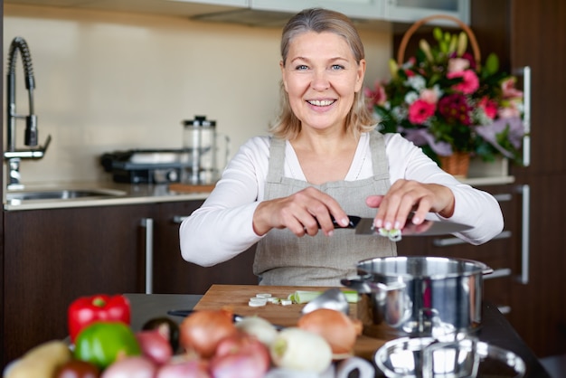 Senior vrouw in de keuken koken, eten mengen in een pot