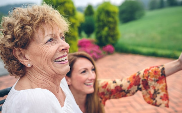 Senior vrouw in een rolstoel met haar dochter die naar het landschap kijkt