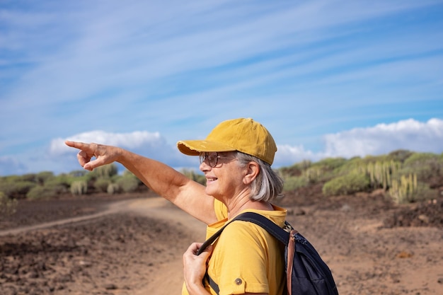 Senior vrouw in geel loopt op een buitenpad op een zonnige dag Weekend toerisme en vrije tijd