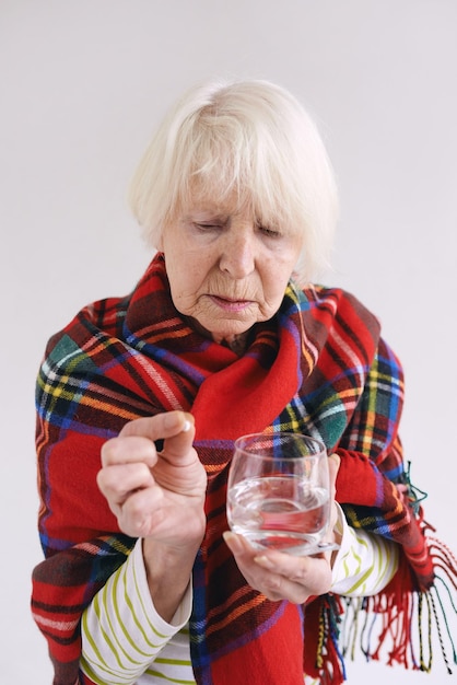 senior vrouw in tartan plaid met pil en glas water Gezondheidszorg volwassen leeftijd ziekte concept