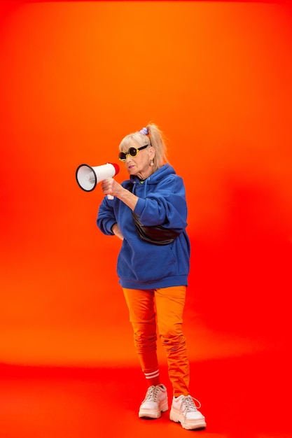 Senior vrouw in ultra trendy kleding geïsoleerd op fel oranje achtergrond