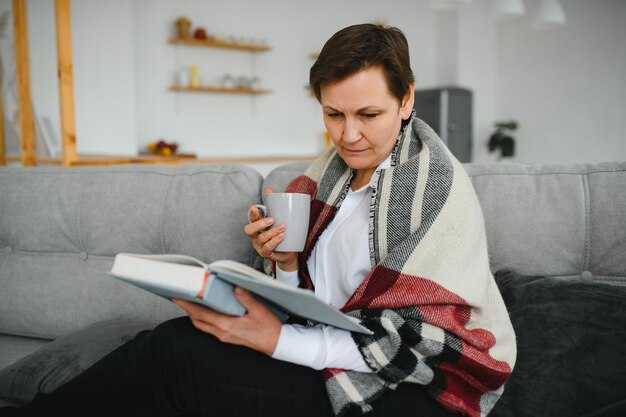 Senior vrouw leesboek thuis