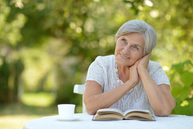 Senior vrouw leest een boek en drinkt thee