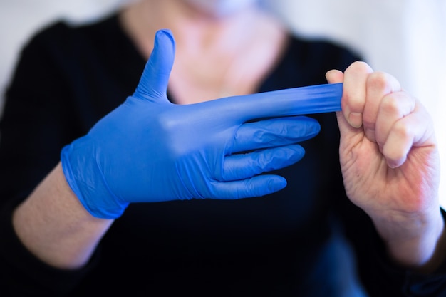 Foto senior vrouw masker dragen en verwijdert de handschoen uit de hand. selectieve aandacht. symptomen van coronavirus en epidemische virussen.