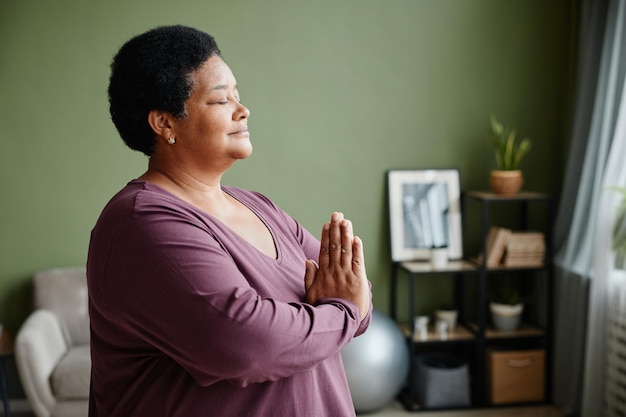 Senior vrouw mediteren thuis zijaanzicht